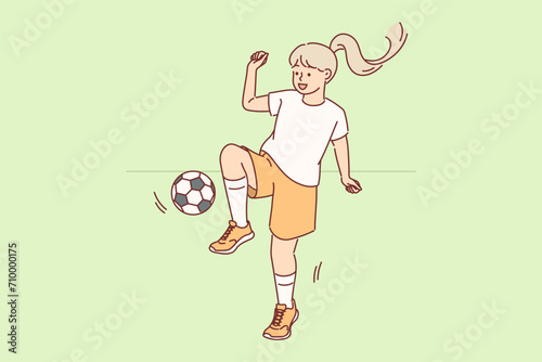 Little girl plays football with ball during outdoor training session preparing for school tournament