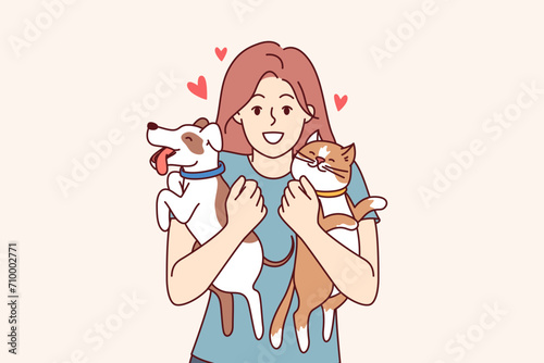 Two pets in hands of teenage girl hugging cat and dog, and feeling love for domesticated animals. Young woman pet owner rejoices at appearance of kitten and puppy, standing among pets