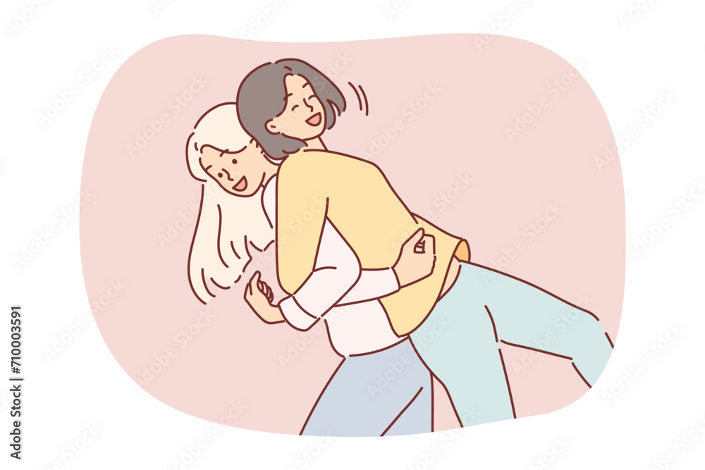 Women friends fool around by lifting each other on backs and laughing to stretch spines Women friends fool around by lifting each other on backs and laughing to stretch spines