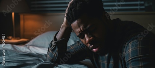 Black man with headache rubbing eyes after waking up, stressed on bed with painful face expression, feeling terrible hangover, weakness or depression.