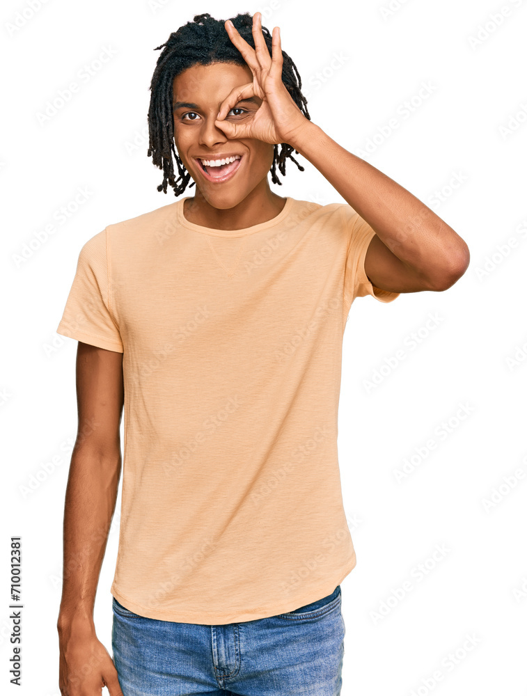 Young african american man wearing casual clothes doing ok gesture with hand smiling, eye looking through fingers with happy face. Young african american man wearing casual clothes doing ok gesture with hand smiling, eye looking through fingers with happy face.
