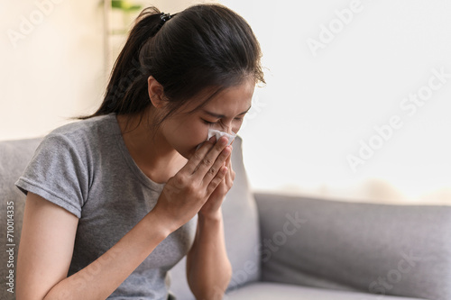 Daily lifestyle or health problem concept : Young Asian woman caught a cold sneezing and have a running nose or fever have to rest at her home and absent from her job.