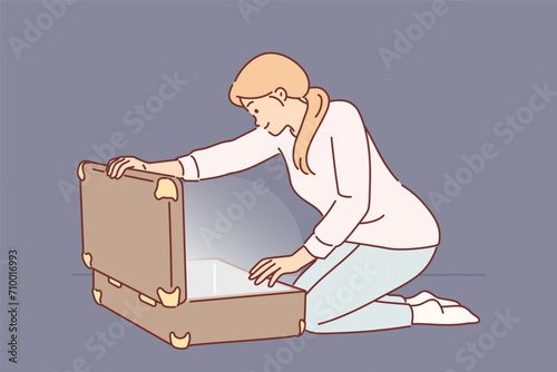 Woman opens large suitcase and sees glow, for concept of discovering treasure with valuables