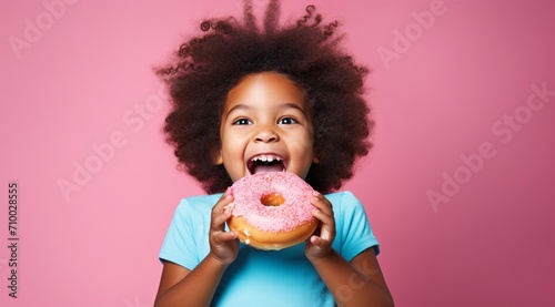 cute child excited about eating a big donut on the blue background, pink photo