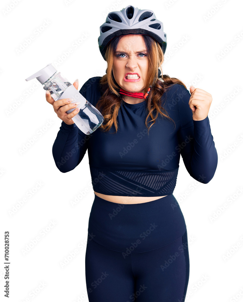 Young beautiful caucasian woman wearing bike helmet and holding water bottle annoyed and frustrated shouting with anger, yelling crazy with anger and hand raised