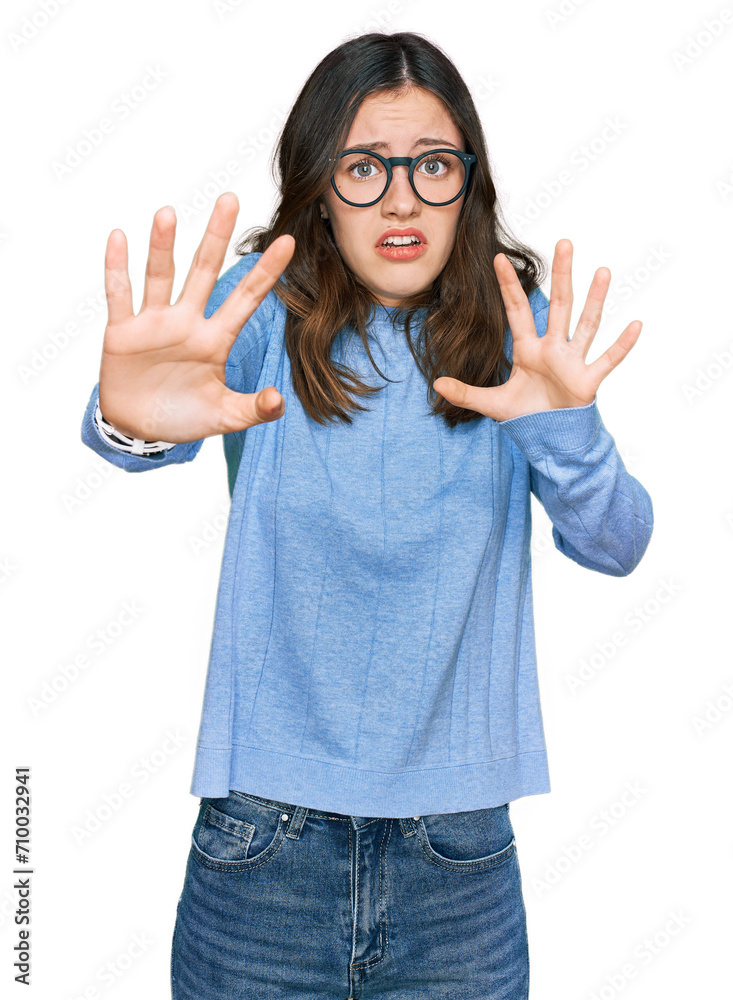Young beautiful woman wearing casual clothes and glasses afraid and terrified with fear expression stop gesture with hands, shouting in shock. panic concept. Young beautiful woman wearing casual clothes and glasses afraid and terrified with fear expression stop gesture with hands, shouting in shock. panic concept.