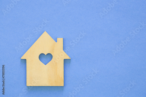 Wooden house model on blue background. House sale or rent, family home and shelter concept, real estate and eco accommodation. Copy space.