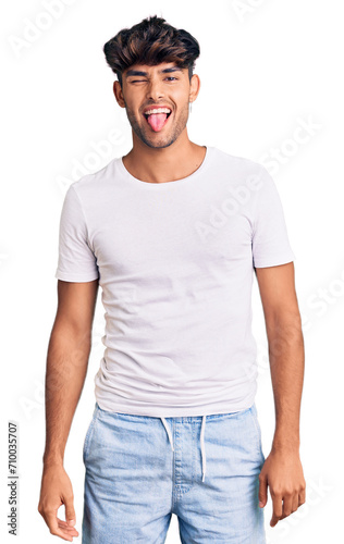 Young hispanic man wearing casual clothes sticking tongue out happy with funny expression. emotion concept.