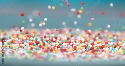 Super slow motion extreme macro of sweet rainbow sugar sprinkles are falling on delicious dessert pink glazed donuts isolated on soft colorful background at 1000 fps. photo