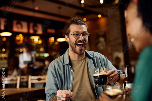 Young man laughing and having fun while drinking beer with girlfriend in pub.