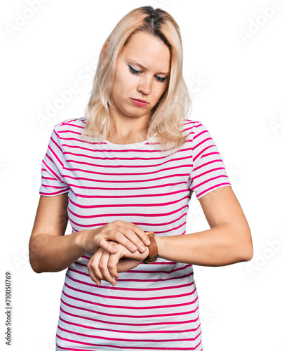Young caucasian woman wearing casual clothes checking the time on wrist watch, relaxed and confident
