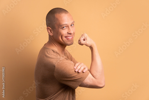 joyful brazilian man flexing arms in all beige colors. strong, power, proud concept. photo