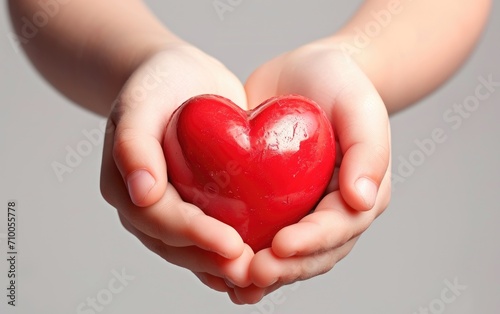 Child s hand holding a red heart  white background