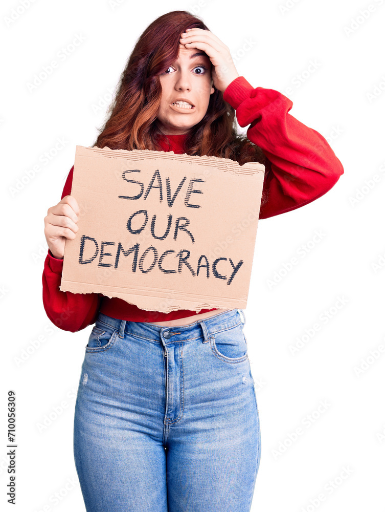 Young beautiful woman holding save our democracy protest banner stressed and frustrated with hand on head, surprised and angry face Young beautiful woman holding save our democracy protest banner stressed and frustrated with hand on head, surprised and angry face