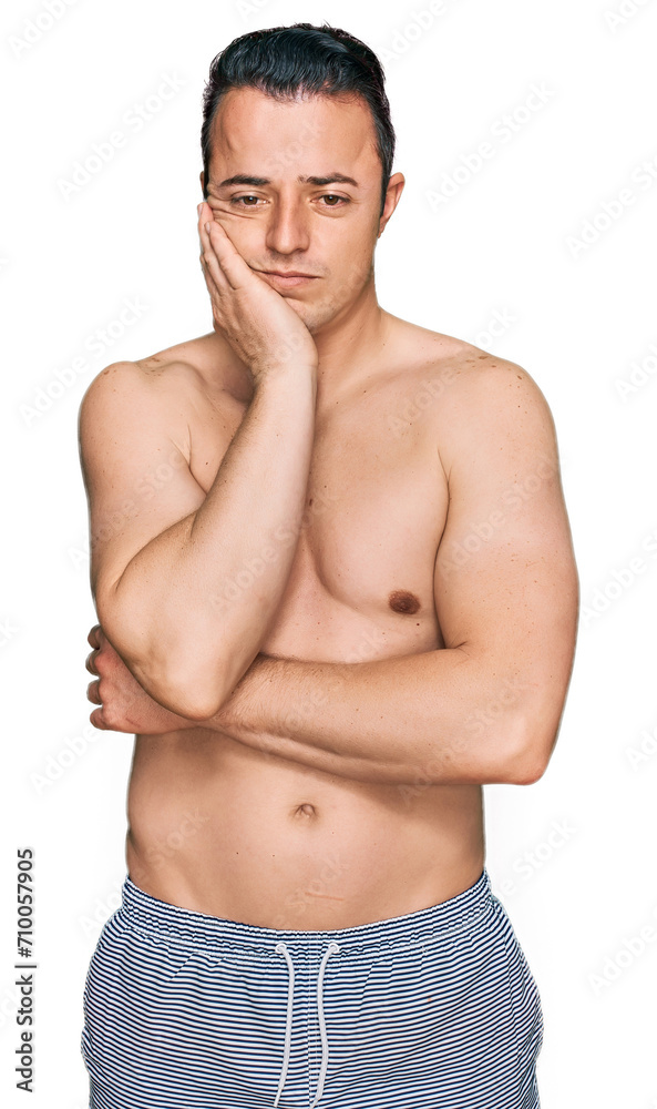 Handsome young man wearing swimwear shirtless thinking looking tired and bored with depression problems with crossed arms.