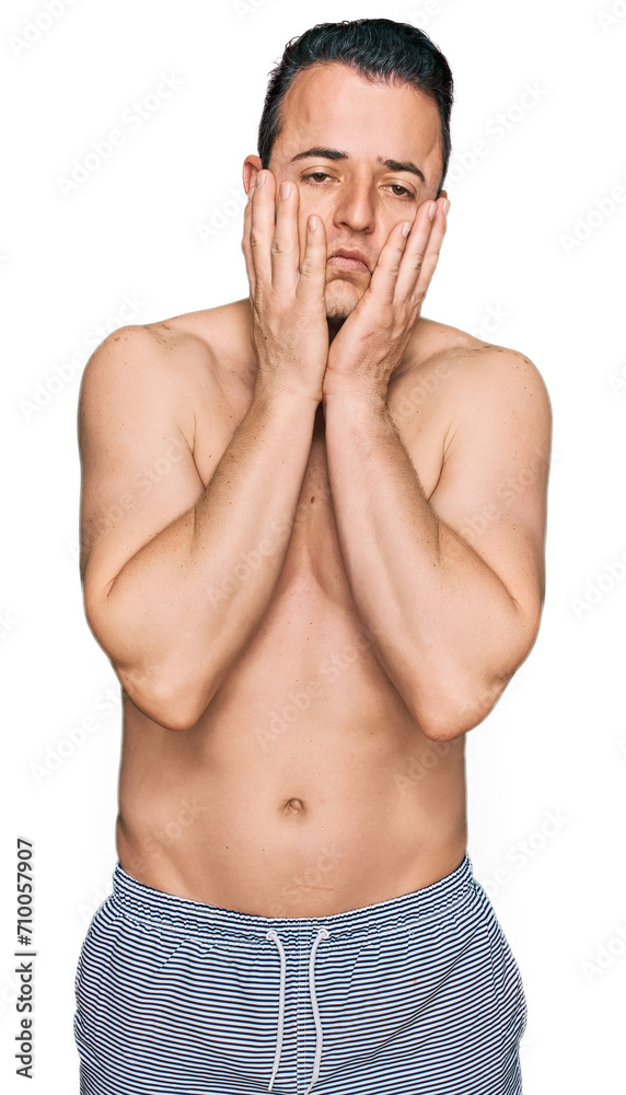 Fototapeta premium Handsome young man wearing swimwear shirtless tired hands covering face, depression and sadness, upset and irritated for problem