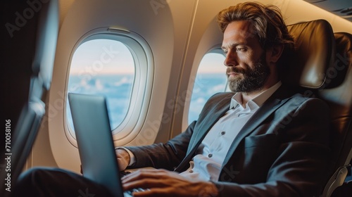 Traveling and technology, Young handsome business man working on laptop while sitting in airplane by the window. Generative AI. photo