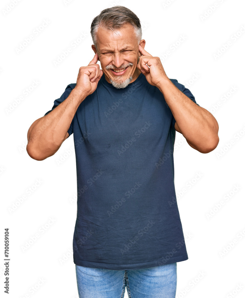 Middle age grey-haired man wearing casual clothes covering ears with fingers with annoyed expression for the noise of loud music. deaf concept. Middle age grey-haired man wearing casual clothes covering ears with fingers with annoyed expression for the noise of loud music. deaf concept.