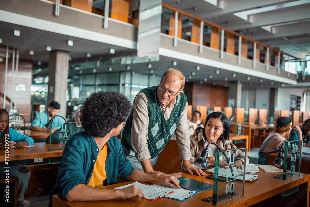 Professor assisting college students in library Professor assisting college students in library