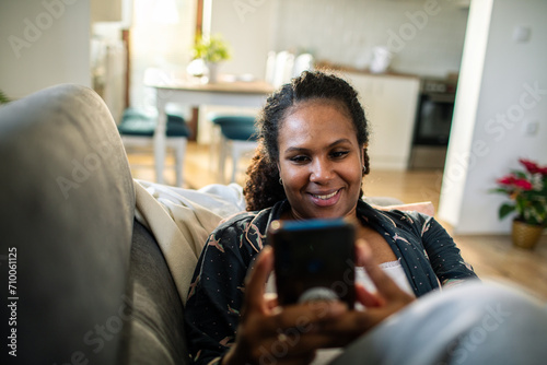 Relaxed woman using smartphone on couch at home photo