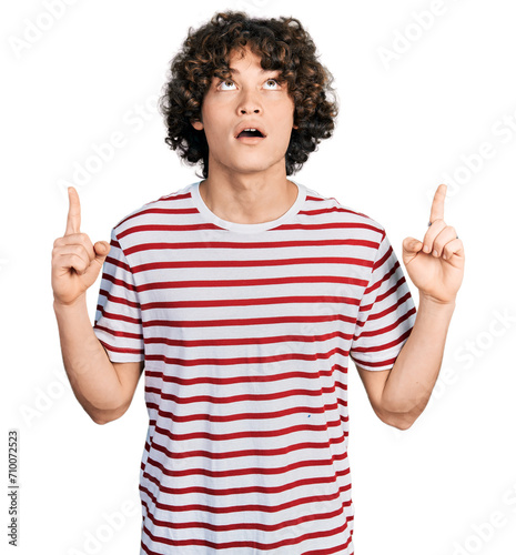 Caucasian teenager wearing casual clothes amazed and surprised looking up and pointing with fingers and raised arms.