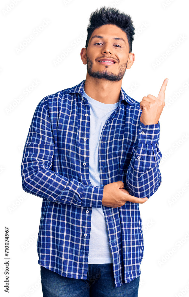 Handsome latin american young man wearing casual shirt smiling happy pointing with hand and finger to the side Handsome latin american young man wearing casual shirt smiling happy pointing with hand and finger to the side
