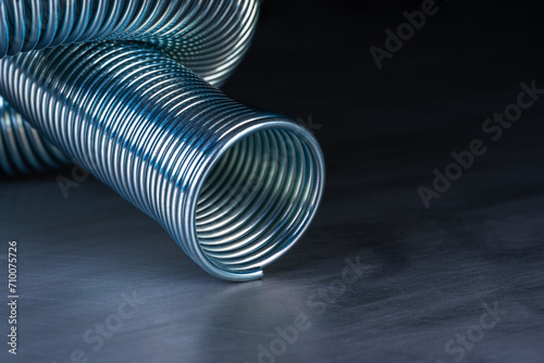 Coiled metal spring on metal surface, close-up view photo