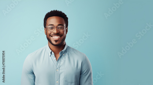 A cheerful man in light blue exudes casual professionalism with a broad smile standing isolated on turquoise backdrop, ideal for creative industries and casual corporate profiles.