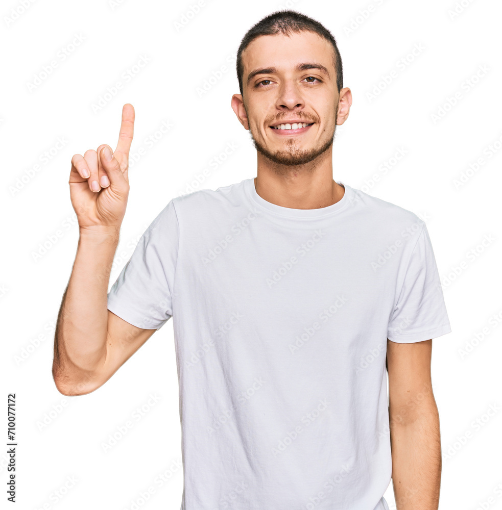 Fototapeta premium Hispanic young man wearing casual white t shirt showing and pointing up with finger number one while smiling confident and happy.