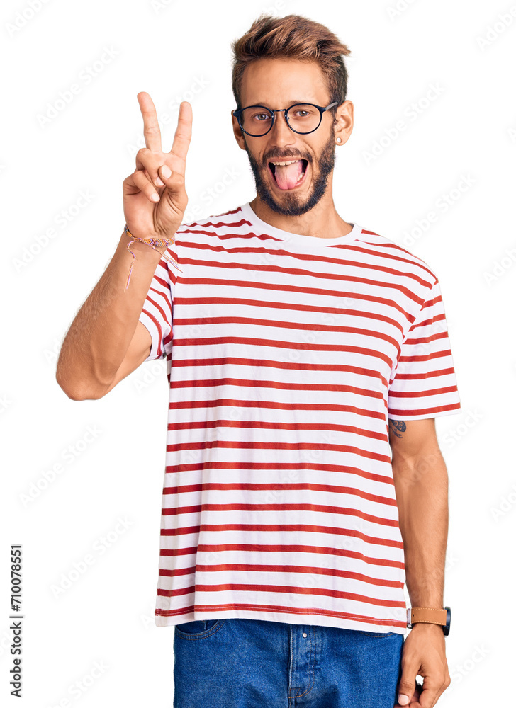 Handsome blond man with beard wearing casual clothes and glasses smiling with happy face winking at the camera doing victory sign with fingers. number two.