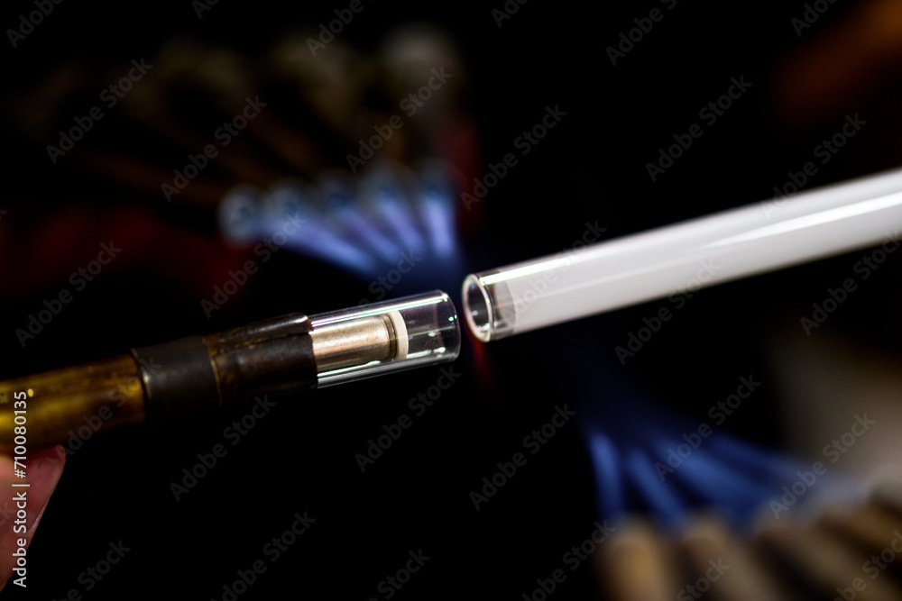 Naklejka premium neon glass blower using fire to melt electrode to neon glass tube