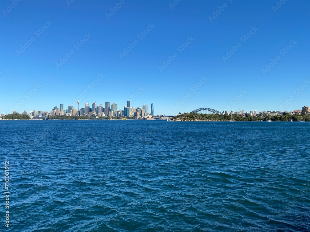 City skyline from the ocean shore. View of Sydney and its iconic buildings, skyscrapers and bridge at the distance. Australian city on the horizon.