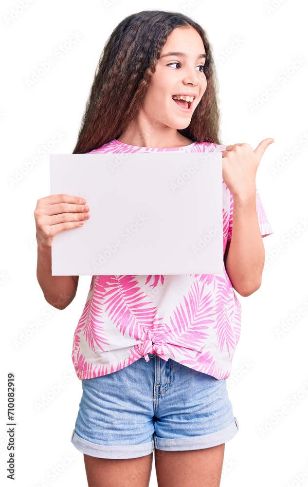 Cute hispanic child girl holding blank empty banner pointing thumb up to the side smiling happy with open mouth Cute hispanic child girl holding blank empty banner pointing thumb up to the side smiling happy with open mouth