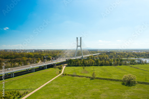 Pylon bridge with cars over green island on Oder river in Wroclaw. Cable-stayed Redzinski Bridge and scenic spring landscape aerial view