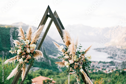 Triangular wedding tipi arch decorated with flowers stands on a mountain above the Kotor Bay. Montenegro photo