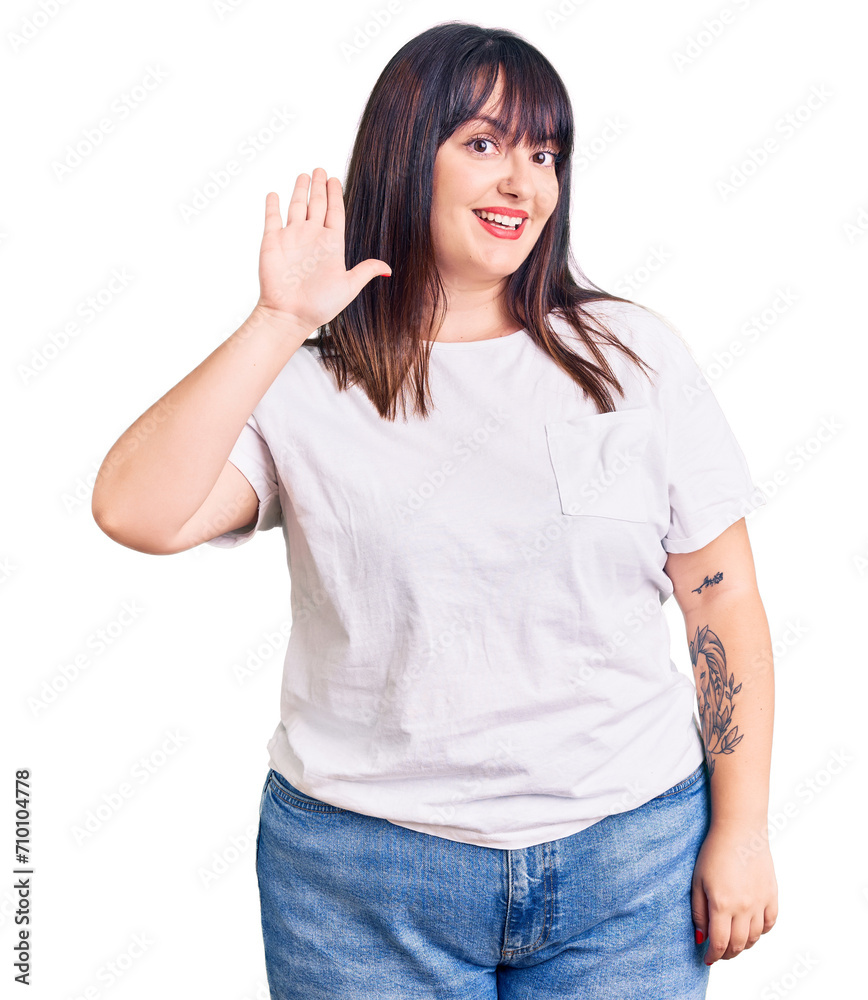 Young plus size woman wearing casual clothes waiving saying hello happy and smiling, friendly welcome gesture Young plus size woman wearing casual clothes waiving saying hello happy and smiling, friendly welcome gesture
