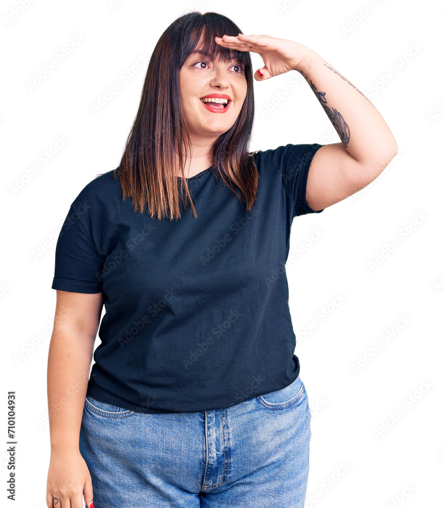 Young plus size woman wearing casual clothes very happy and smiling looking far away with hand over head. searching concept. Young plus size woman wearing casual clothes very happy and smiling looking far away with hand over head. searching concept.