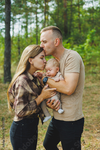 Happy family couple with little newborn son in nature. Happy young mother and father with a child on a walk in the forest. The concept of a happy married couple with a child © Дмитрий Ткачук