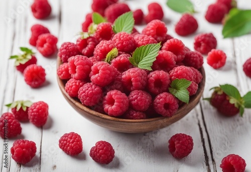 Ripe sweet raspberries in bowl on white wooden background