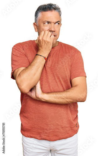 Handsome middle age man wearing casual clothes looking stressed and nervous with hands on mouth biting nails. anxiety problem.