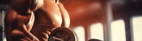 A man works out in the gym, close-up of a dumbbell and muscles. Banner.