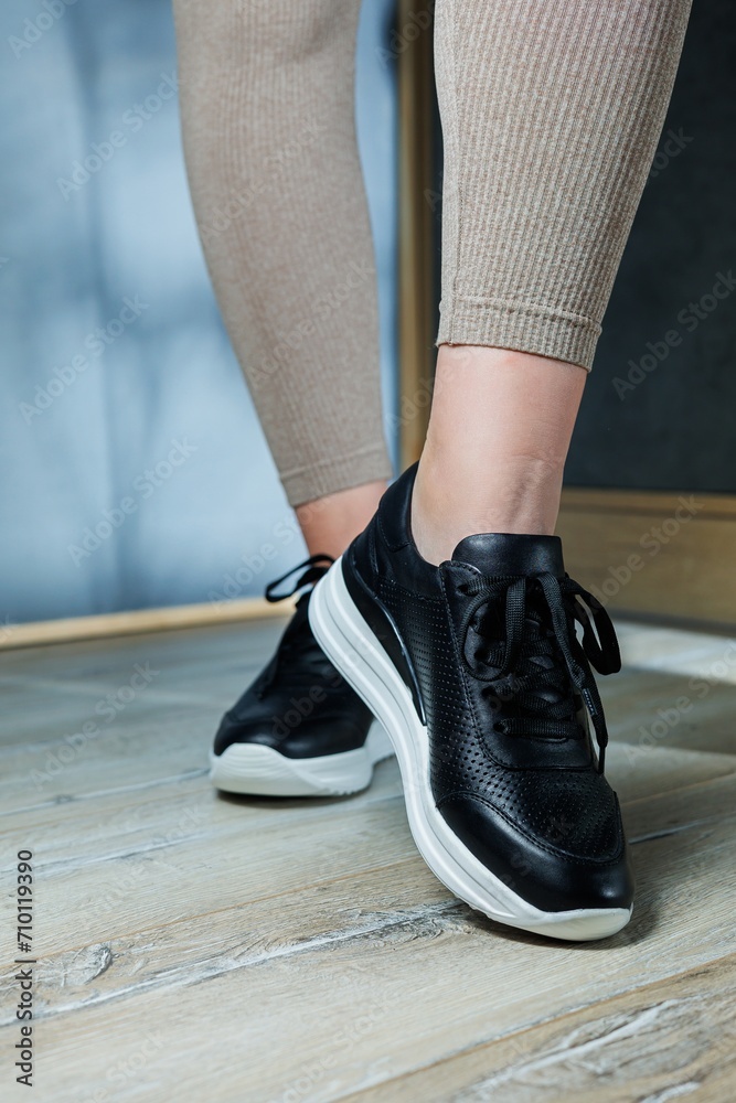 Black women's sneakers. Collection of women's leather shoes. Female legs in leather black casual sneakers. Stylish women's sneakers.