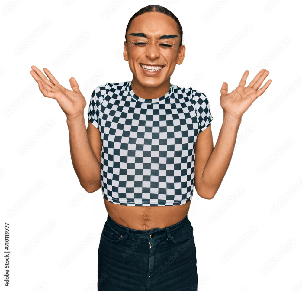 Hispanic transgender man wearing make up and long hair wearing modern clothes celebrating mad and crazy for success with arms raised and closed eyes screaming excited. winner concept