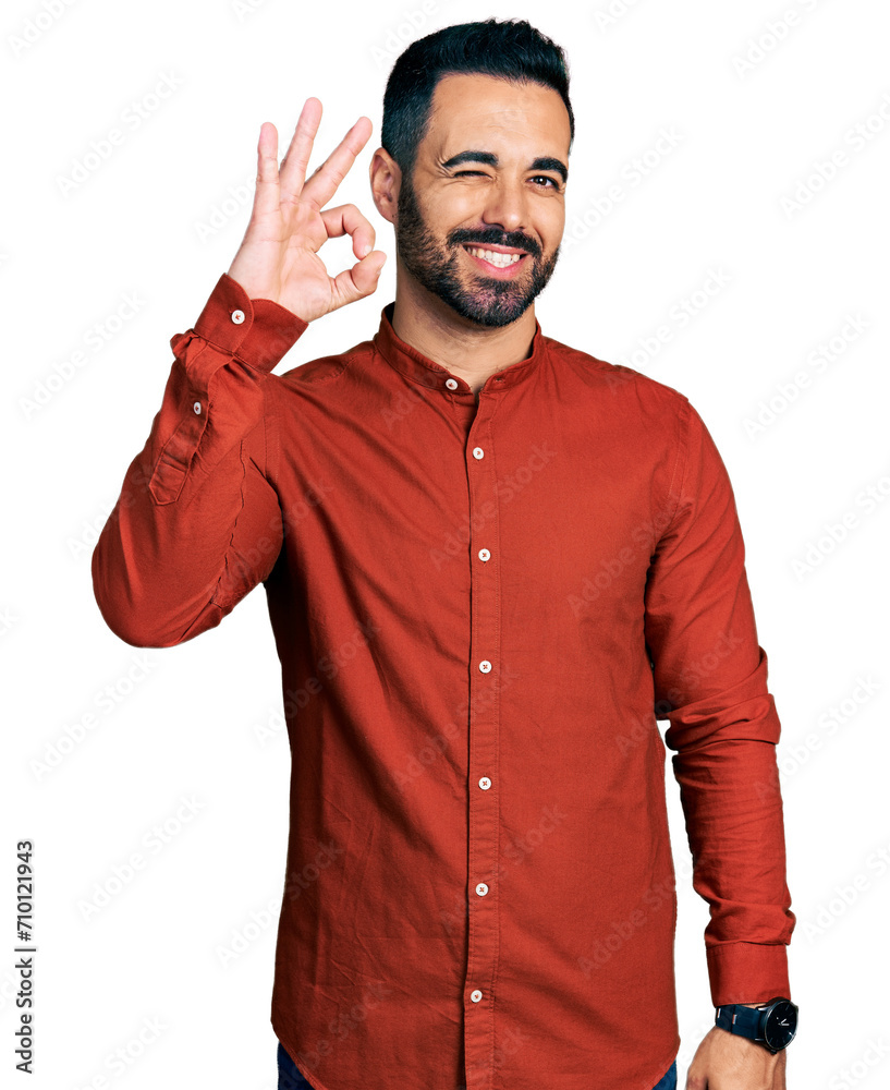 Young hispanic man with beard wearing casual shirt smiling positive doing ok sign with hand and fingers. successful expression.