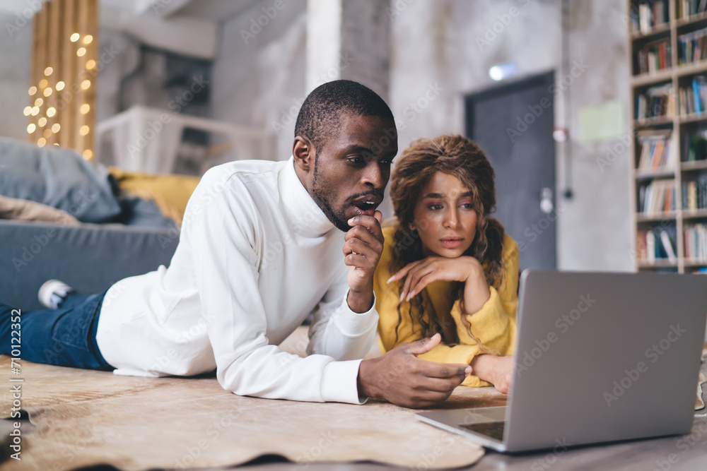 Thoughtful couple engaged with laptop in their new home, focus and planning amidst the warm, inviting ambiance of their modern living space. Shocked man check online banking app on computer Thoughtful couple engaged with laptop in their new home, focus and planning amidst the warm, inviting ambiance of their modern living space. Shocked man check online banking app on computer