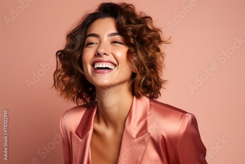 Portrait of a beautiful happy young woman laughing over pink background.