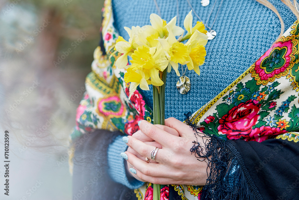 Traditional Elegance - woman in folk costume with spring daffodils outdoors.