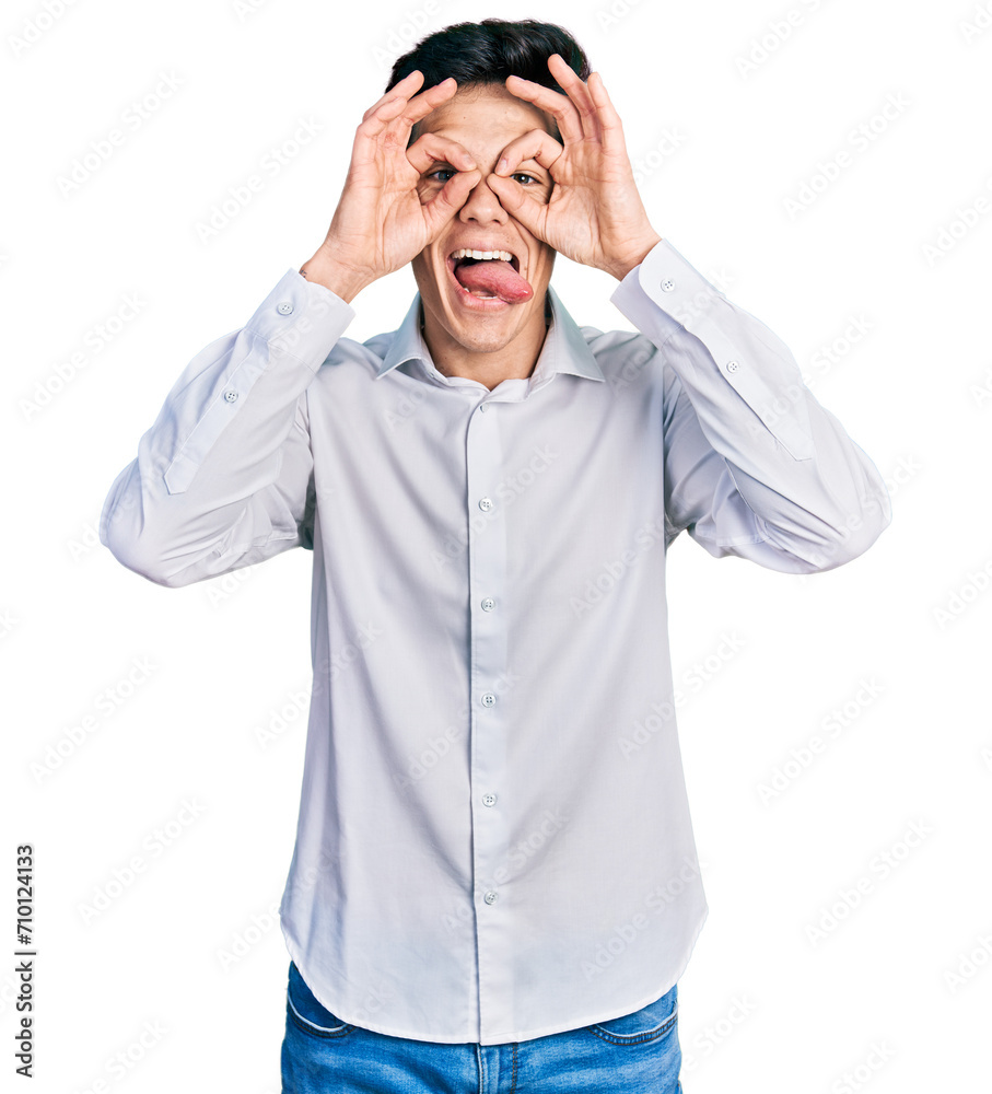 Naklejka premium Young hispanic business man wearing business clothes doing ok gesture like binoculars sticking tongue out, eyes looking through fingers. crazy expression.