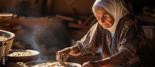 Elderly Arab woman cooking traditional Bedouin cuisine, preparing fresh dough for flatbread. photo