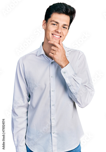 Young hispanic business man wearing business clothes looking confident at the camera with smile with crossed arms and hand raised on chin. thinking positive.